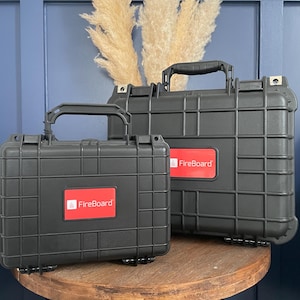 May include: Two black hard-shell cases with the logo "FireBoard" in red on the front. The cases are sitting on a wooden table.