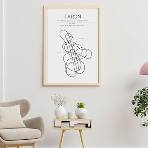 Könnte beinhalten: Ein gerahmter Kunstdruck mit dem Wort "TARON" oben, der eine schwarze Strichzeichnung einer Achterbahnstrecke zeigt. Der Druck enthält Text, der den Standort als Phantasialand, Deutschland, angibt. Das Kunstwerk wird in einem Wohnzimmer gezeigt.
