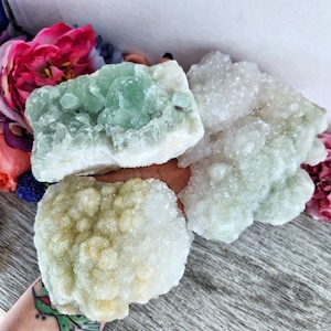 May include: Three pieces of green and white crystal clusters. The largest cluster is green with white edges. The other two clusters are white with green accents.