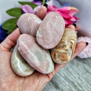 May include: Five smooth, polished stones in shades of pink and white. The stones are oval shaped and have a natural, marbled appearance.
