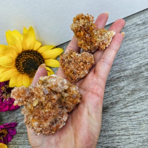 May include: Three clusters of orange and white calcite crystals. The crystals are clustered together in a rough, natural formation.