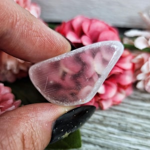 May include: A clear, triangular piece of selenite crystal with a smooth, polished surface. The crystal is translucent and has a slight shimmer.