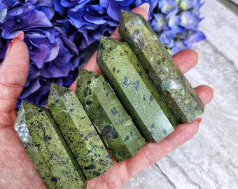 May include: Five green serpentine stone points with a speckled pattern. The points are arranged in a row, with the largest point at the top and the smallest point at the bottom.