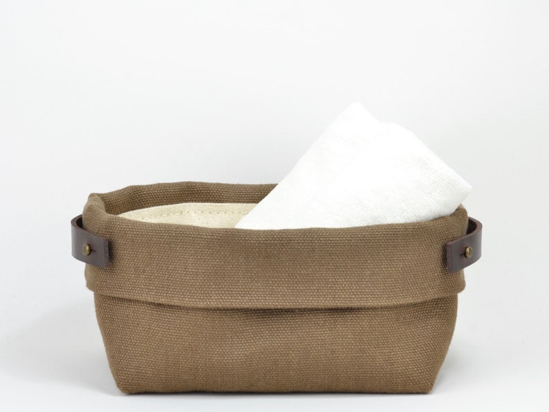 Natural Belgian bristol linen rectangular basket lined in organic cotton canvas. Detachable leather handles with button stud details. The cuff can be unrolled and extended.