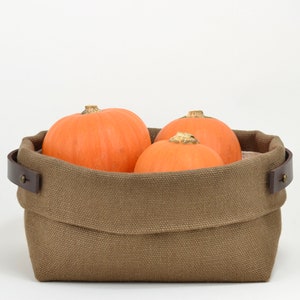 Natural Belgian bristol linen rectangular basket lined in organic cotton canvas. Detachable leather handles with button stud details. The cuff can be unrolled and extended.