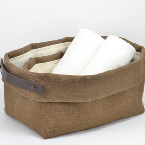 Natural Belgian bristol linen rectangular basket lined in organic cotton canvas. Detachable leather handles with button stud details. The cuff can be unrolled and extended.