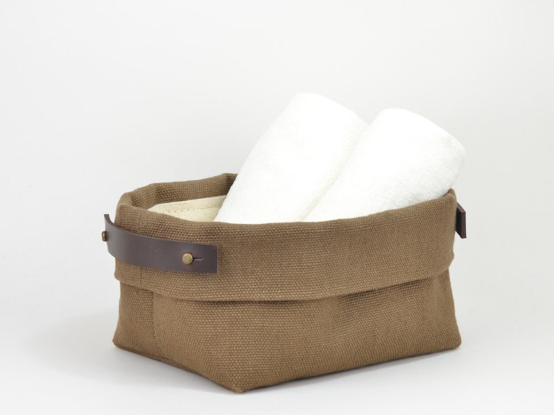 Natural Belgian bristol linen rectangular basket lined in organic cotton canvas. Detachable leather handles with button stud details. The cuff can be unrolled and extended.