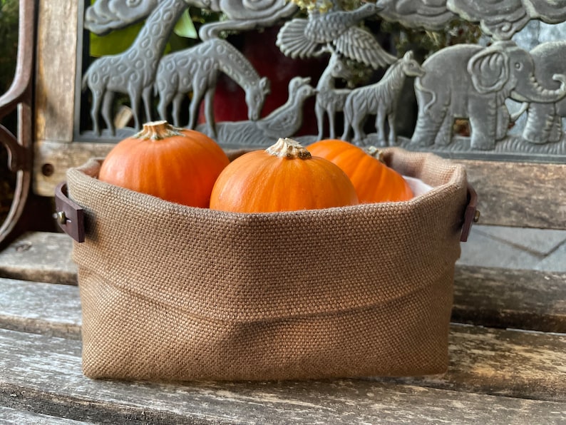 Natural Belgian bristol linen rectangular basket lined in organic cotton canvas. Detachable leather handles with button stud details. The cuff can be unrolled and extended.