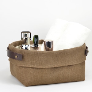 Natural Belgian bristol linen rectangular basket lined in organic cotton canvas. Detachable leather handles with button stud details. The cuff can be unrolled and extended.