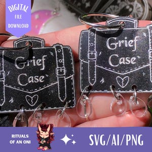 May include: Two black Grief Case charms with silver key rings. Each charm features a briefcase design with the words "Grief Case" and a broken heart. The charms have clear, teardrop-shaped accents. The image also includes the text "DIGITAL FILE DOWNLOAD" and "SVG/AI/PNG".