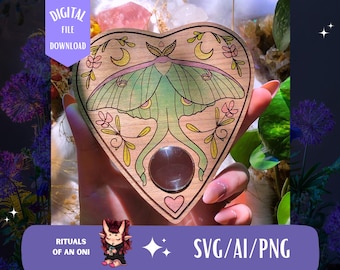 May include: A heart-shaped wooden planchette with a luna moth design. The moth is green and pink, with yellow accents. The planchette has a clear, round window and is decorated with flowers and crescent moons. Text on the image reads "DIGITAL FILE DOWNLOAD" and "SVG/AI/PNG".