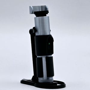 May include: A 3D printed lightsaber prop with a black handle and a silver blade. The lightsaber is on a black stand.