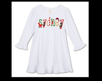 May include: White long-sleeved dress with a ruffled hem and sleeves. The dress has a Christmas-themed design with the name "sydney" spelled out in colorful letters with festive embellishments.