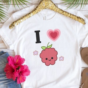 May include: White t-shirt with a graphic design of a raspberry with a smiling face and the text "I love" with a pink heart.