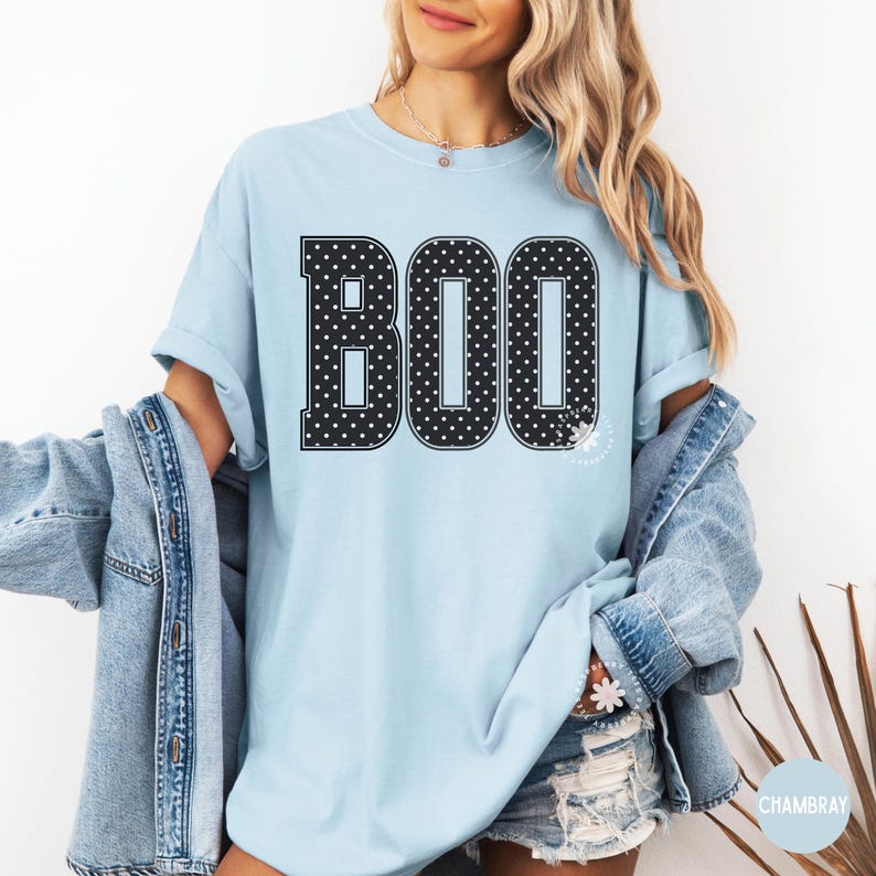 Puede incluir: Una camiseta de cuello redondo en color azul claro con la palabra BOO impresa en letras grandes de bloque negro con un patr&oacute;n de puntos blancos. La prenda se combina con una chaqueta vaquera azul claro y pantalones cortos de mezclilla.