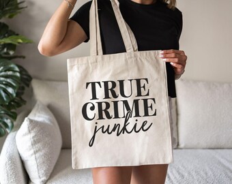 May include: A white canvas tote bag with black text that reads "TRUE CRIME junkie".