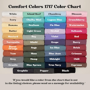 Puede incluir: Una carta de colores Comfort Colors 1717 que muestra muestras de tela dobladas en varios tonos. El texto dice Comfort Colors 1717 Color Chart e incluye una lista de nombres de colores como White, Ivory, Banana, Mustard, Terracotta y Black.