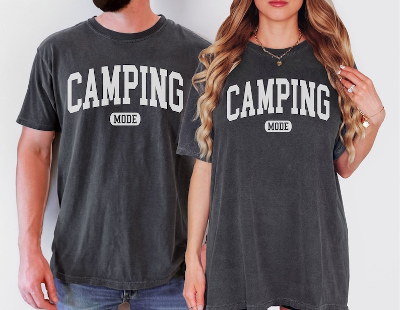 May include: Two black t-shirts with white text that reads "Camping Mode".