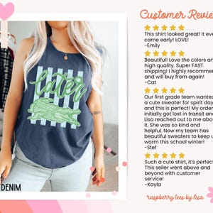May include: Denim tank top with a green alligator graphic and the word "later" in a playful font. The shirt has a relaxed fit and a faded, vintage look. The text "DENIM" is at the bottom left.