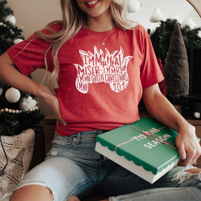 May include: A red t-shirt with a white graphic that says "I'm Mr. Heat Miser - I'm Mr. Sun I'm Mr. Green Christmas I'm Mr."