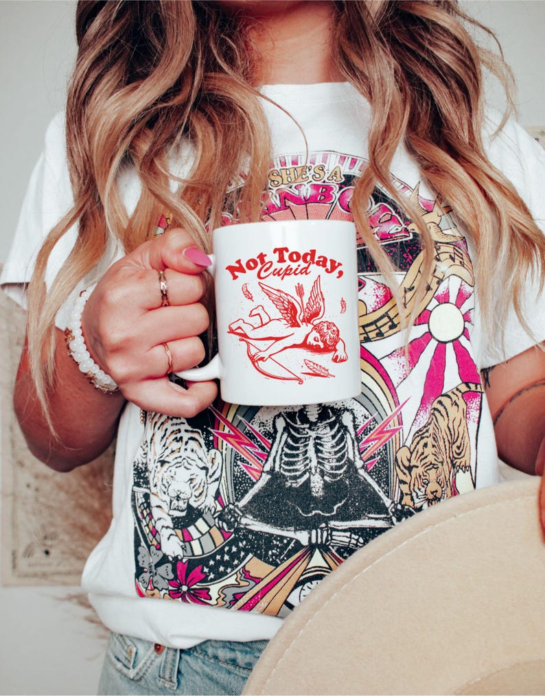 May include: White ceramic mug with a red graphic of a winged cupid with an arrow and the text "Not Today, Cupid".
