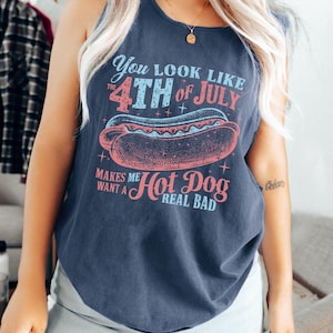 Puede incluir: Una camiseta sin mangas azul marino con el texto "You look like the 4th of July makes me want a hot dog real bad" y un gr&aacute;fico de un perrito caliente. El texto y el gr&aacute;fico son en rojo, azul y rosa.