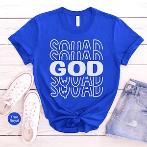 Pu&ograve; includere: Una maglietta blu reale con una grafica bianca che dice "God Squad" in un font retr&ograve;.