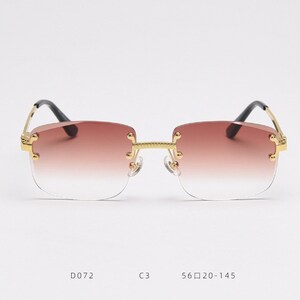Puede incluir: Gafas de sol con montura dorada y lentes de degradado marr&oacute;n. Las gafas tienen un dise&ntilde;o sin montura y est&aacute;n etiquetadas con el n&uacute;mero de modelo D072, el color C3 y la talla 56□20-145.