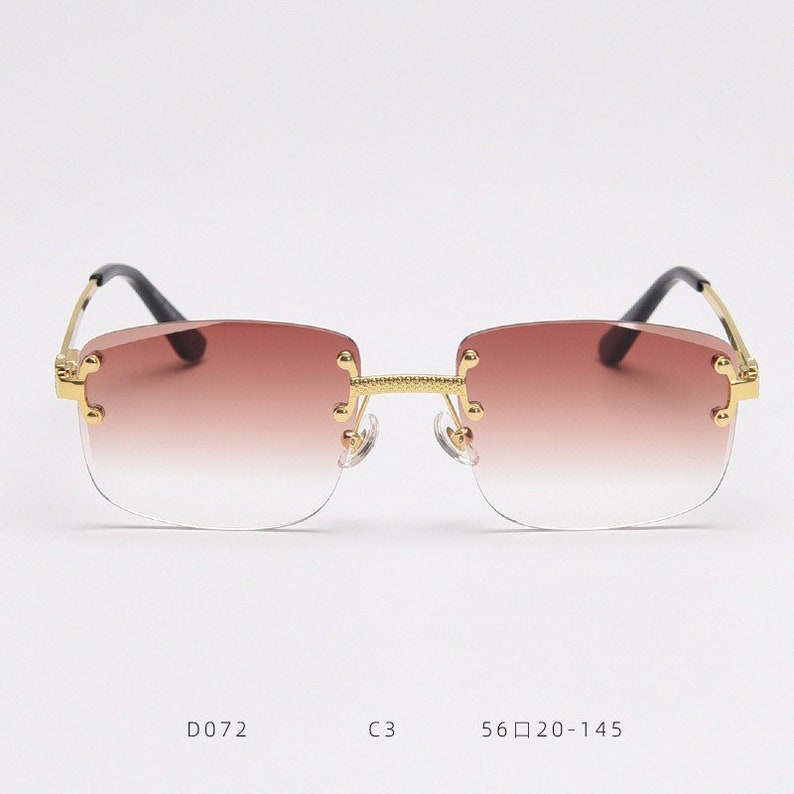 Puede incluir: Gafas de sol con montura dorada y lentes de degradado marr&oacute;n. Las gafas tienen un dise&ntilde;o sin montura y est&aacute;n etiquetadas con el n&uacute;mero de modelo D072, el color C3 y la talla 56□20-145.