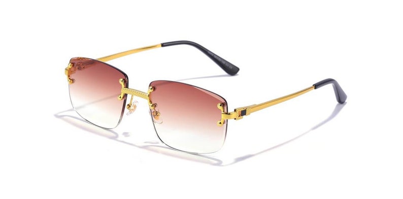 Puede incluir: Gafas de sol con montura dorada y lentes de degradado marr&oacute;n. Las gafas tienen un dise&ntilde;o sin montura y un fino marco dorado.