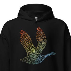 Puede incluir: Sudadera con capucha negra con un diseño de pájaro estilizado lleno de texto multicolor. El texto incluye palabras como "Seekers", "Elmer" y "Fiction". El gráfico del pájaro está centrado en el pecho.