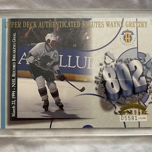 May include: A hockey card encased in a clear acrylic holder. The card features a photo of Wayne Gretzky on the ice, with the number "802" prominently displayed. Text includes "Upper Deck Authenticated" and "Limited Edition".