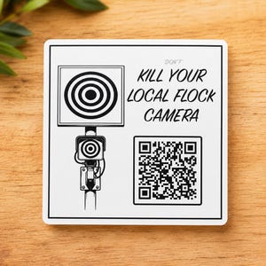 May include: A square white sticker with a black border featuring a graphic of a surveillance camera with a target symbol. The text reads DON'T KILL YOUR LOCAL FLOCK CAMERA in black capital letters, accompanied by a square QR code in the bottom right.