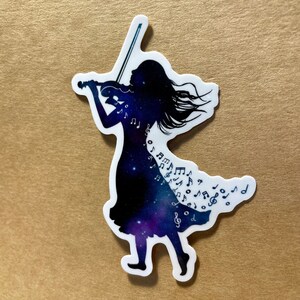 K&ouml;nnte beinhalten: Ein Aufkleber mit der Silhouette einer Person, die Geige spielt. Das Kleid der Person ist mit einem Galaxiemuster und Noten gef&uuml;llt.