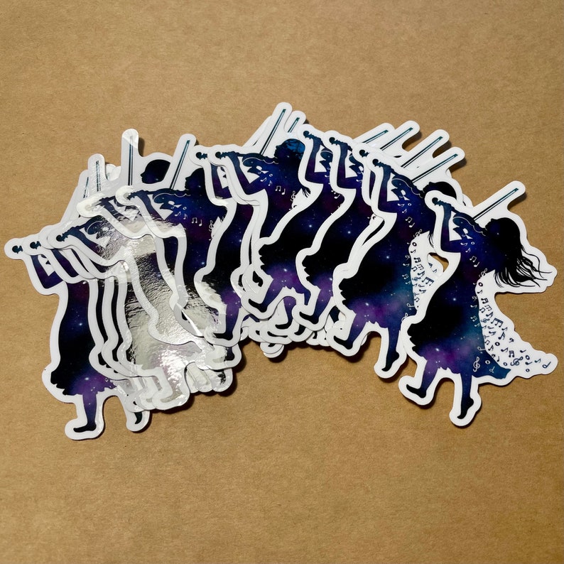 K&ouml;nnte beinhalten: Ein Satz silberner Vinyl-Aufkleber mit der Silhouette einer Gruppe von Menschen, die Geige spielen. Die Silhouetten sind vor einem dunkelblauen Hintergrund mit wei&szlig;en Noten platziert.