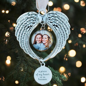 May include: Silver angel wing ornament with a photo insert and a charm that reads "a piece of my heart is in heaven".