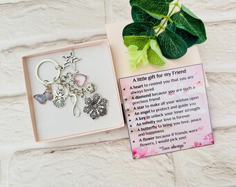 May include: A keychain gift set for a friend, presented in a pink box. The keychain features charms including a butterfly, star, heart, angel, and flower. A card with text is included.