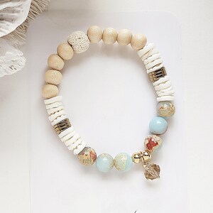 May include: A beaded bracelet featuring a combination of natural wood, white shell, and blue and brown agate beads. The bracelet has a gold charm.