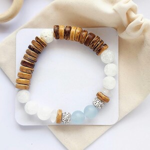 May include: A brown, white and blue beaded bracelet with wooden beads, white lava beads and light blue glass beads.