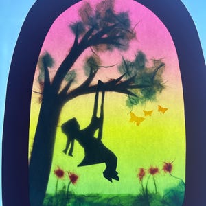 Puede incluir: Una obra de arte en papel recortado que presenta la silueta negra de una persona en un columpio que cuelga de un árbol. El fondo es un degradado vibrante de rosa, amarillo y verde. Se ven tres pequeñas mariposas amarillas y flores rojas.