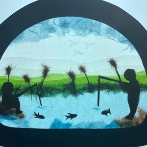 Puede incluir: Una pieza de arte en papel semicircular con siluetas negras de dos figuras pescando en una escena de agua azul claro. El fondo incluye colinas verdes, juncos marrones y tres aves en vuelo. Tres siluetas de peces negros nadan en la parte inferior.