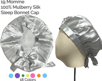May include: A silver-gray sleep bonnet made of 100% mulberry silk. The bonnet has a gathered design with a satin ribbon tie. The text on the image reads "19 Momme 100% Mulberry Silk Sleep Bonnet Cap" and "18 Colors".