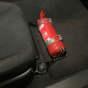 Toyota GT86 fire extinguisher holder bracket mounted on OEM seat rails. Ensure safety with easy access to the fire extinguisher while driving. A reliable addition to your GT86 for emergency situations