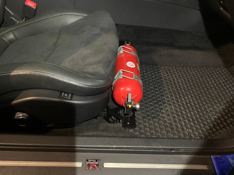 Nissan GTR R35 fire extinguisher holder bracket mounted on OEM seat rails. Ensure safety with this easy-to-access and sturdy bracket for emergencies. Perfect fit for your GTR R35