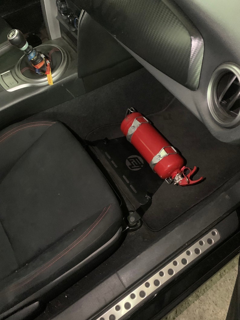 Toyota GT86 fire extinguisher holder bracket mounted on OEM seat rails. Ensure safety with easy access to the fire extinguisher while driving. A reliable addition to your GT86 for emergency situations