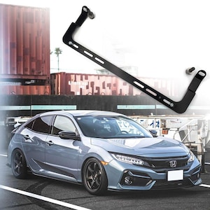 Puede incluir: Un Honda Civic plateado con un alerón trasero negro y llantas negras. El coche está aparcado en una superficie pavimentada. Un soporte metálico negro se muestra por encima del coche.