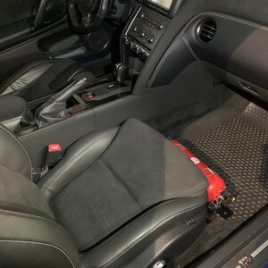 Nissan GTR R35 fire extinguisher holder bracket mounted on OEM seat rails. Ensure safety with this easy-to-access and sturdy bracket for emergencies. Perfect fit for your GTR R35