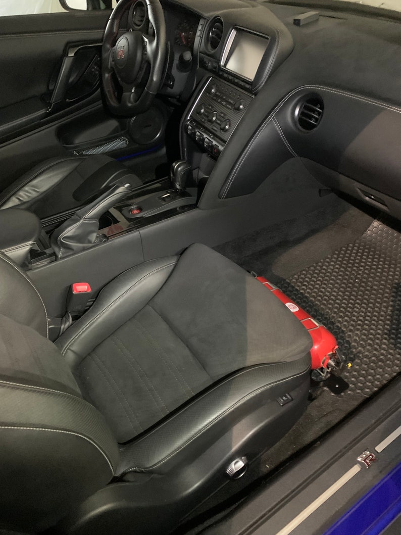 Nissan GTR R35 fire extinguisher holder bracket mounted on OEM seat rails. Ensure safety with this easy-to-access and sturdy bracket for emergencies. Perfect fit for your GTR R35
