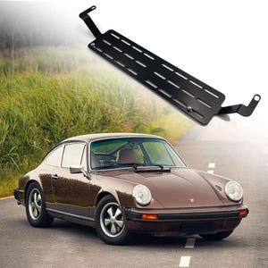 Puede incluir: Un coche clásico marrón con interior negro. El coche tiene una matrícula negra y un parachoques negro. El coche está aparcado en una zona de hierba.