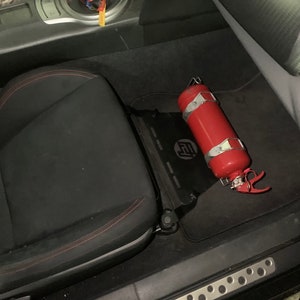 Toyota GT86 fire extinguisher holder bracket mounted on OEM seat rails. Ensure safety with easy access to the fire extinguisher while driving. A reliable addition to your GT86 for emergency situations